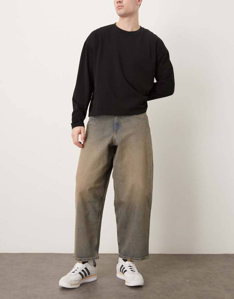 ASOS DESIGN - Schmal zulaufende Oversize-Jeans in mittelblauer Waschung mit braunem Farbstich-Brown von ASOS DESIGN