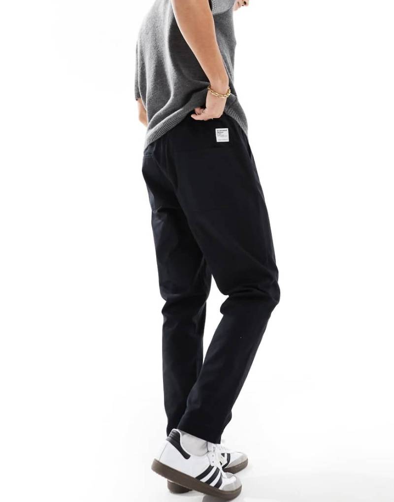 ASOS DESIGN - Schmal zulaufende Schlupfhose in Schwarz mit Aufnäher von ASOS DESIGN