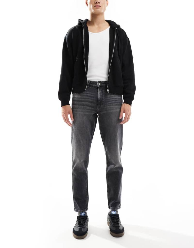 ASOS DESIGN - Schmal zulaufende Stretch-Jeans in verwaschenem Schwarz mit Vintage-Tönung von ASOS DESIGN