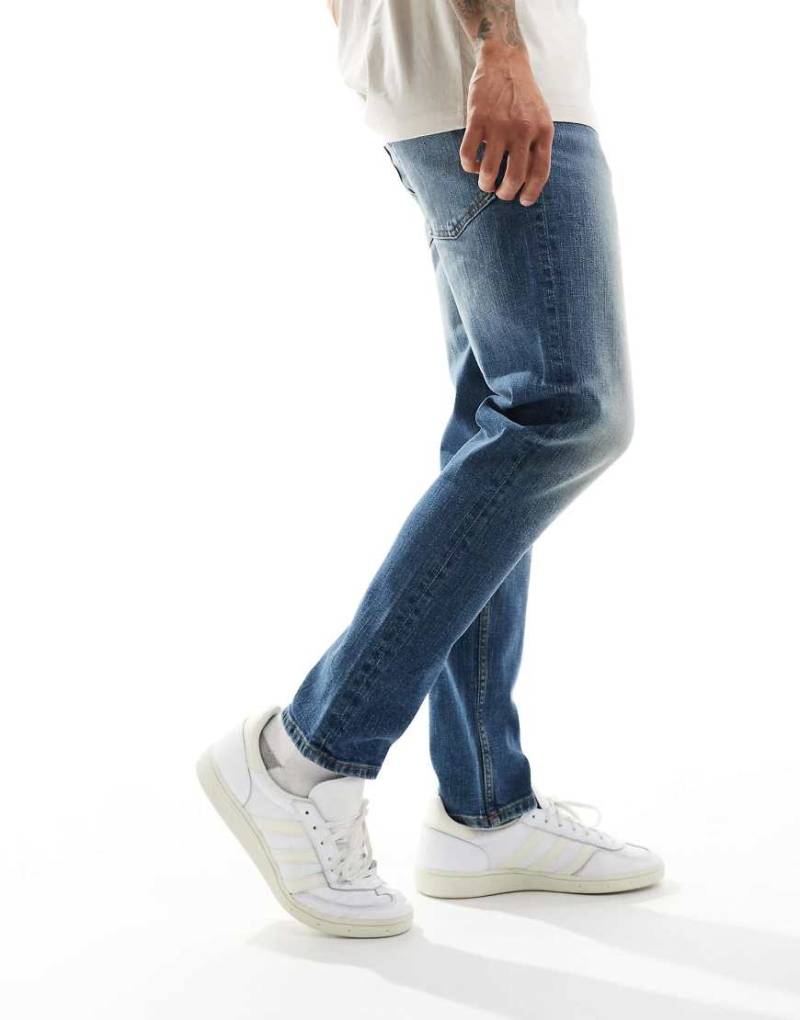 ASOS DESIGN - Schmal zulaufende Stretch-Jeans in verwaschenem Vintage-Mittelblau von ASOS DESIGN