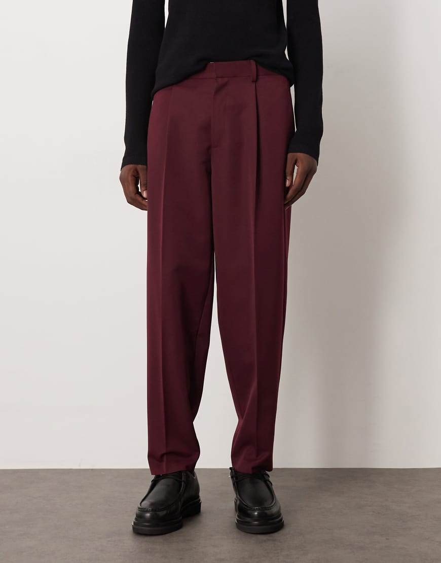ASOS DESIGN - Elegante, schmal zulaufende Oversize-Hose in Burgunderrot mit Bundfalten und elastischem Bund von ASOS DESIGN