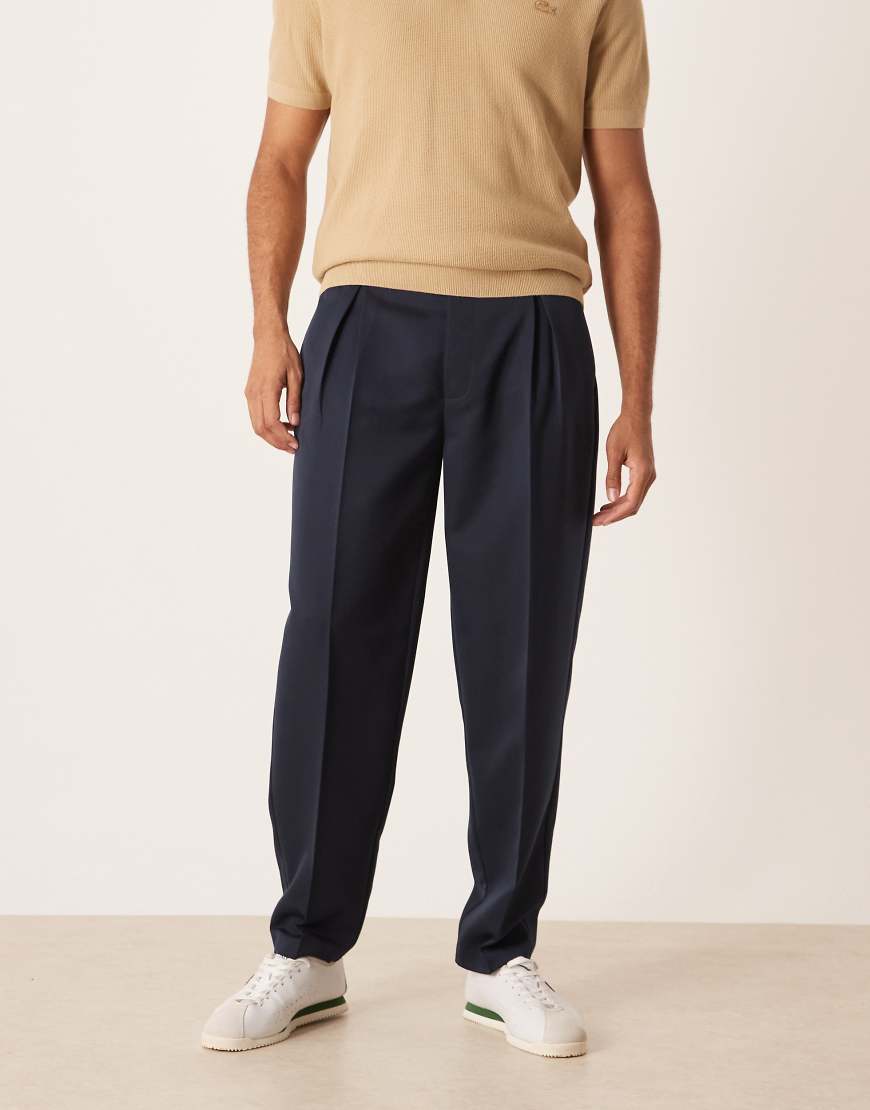 ASOS DESIGN - Smarte, schmal zulaufende Oversize-Hose in Marineblau mit Bundfalten von ASOS DESIGN