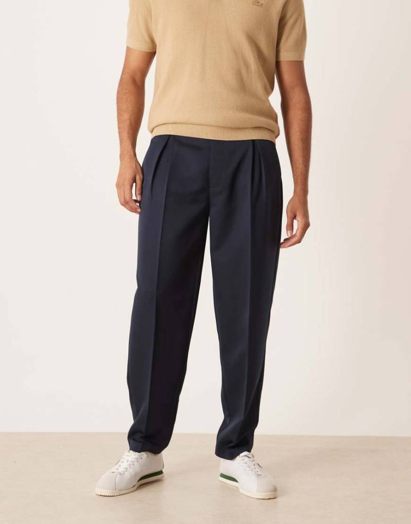 ASOS DESIGN - Smarte, schmal zulaufende Oversize-Hose in Marineblau mit Bundfalten von ASOS DESIGN