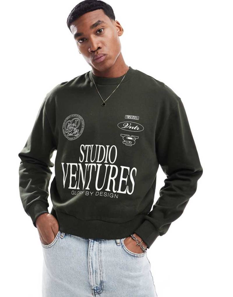 ASOS DESIGN - Sweatshirt in Grün mit überschnittener Schulter und „Studio Ventures"-Print von ASOS DESIGN