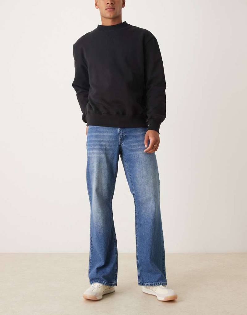ASOS DESIGN - Weit geschnittene Schlagjeans in verwaschenem Mittelblau von ASOS DESIGN