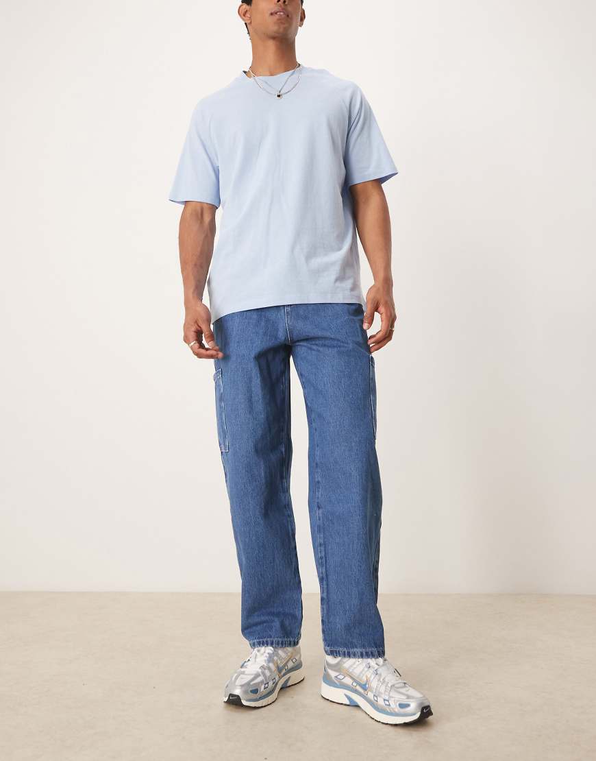 ASOS DESIGN - Weit geschnittene Skater-Jeans in mittelblauer Waschung mit Cargo-Taschen von ASOS DESIGN