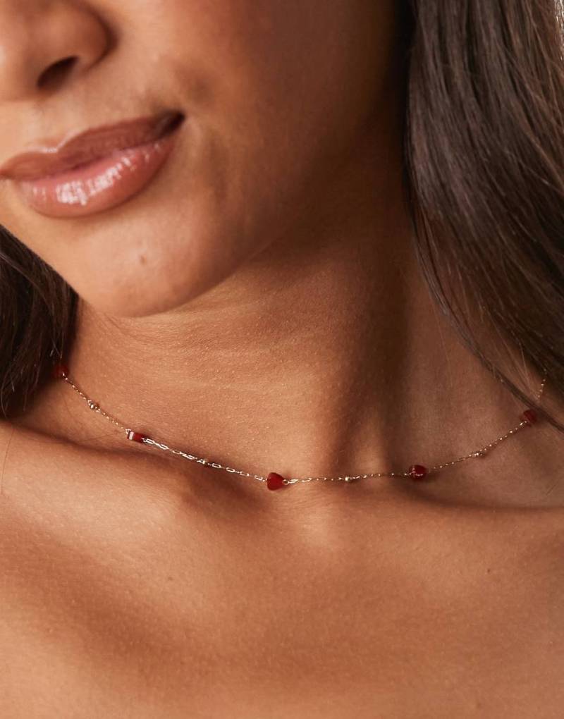 ASOS DESIGN - Zarte, goldfarbene Halskette mit roten herzförmigen Halbedelsteinen von ASOS DESIGN