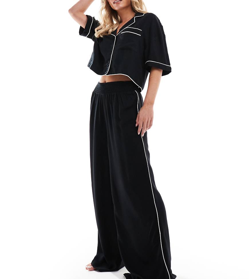 ASOS DESIGN Petite - Superweiche, fließende Pyjama-Hose in Schwarz mit kontrastierender Einfassung und weitem Bein von ASOS Petite
