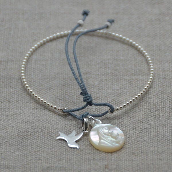 Weiches Silbernes Perlenarmband Mit Einem Silbernen Taubenanhänger Und Einer Perlmuttmedaille Weiches Silbernes Perlenarmband Mit Einem Silbernen Taubenanhänger Und Einer Perlmuttmedaille von AlabridesLezards