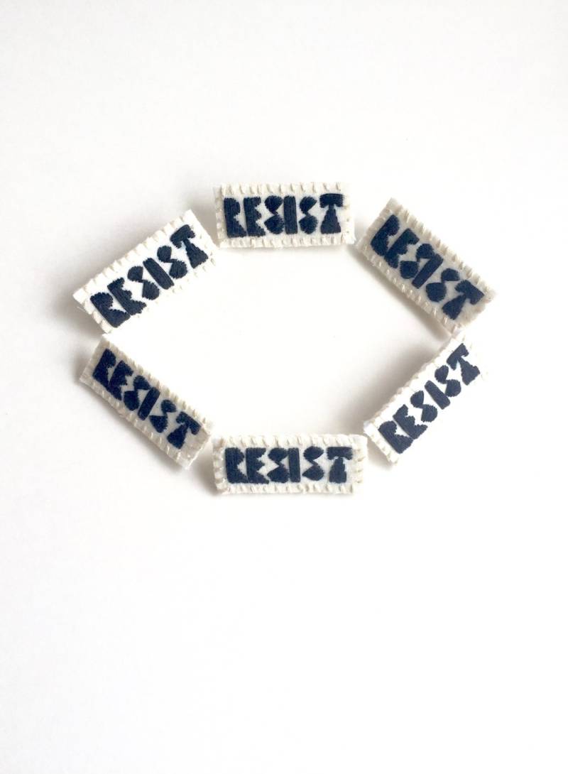 Handgestickte Brosche "Resist" Schwarzer Faden Auf Hellem Musselin Mit Stabiler Cremefarbener Filzrückseite Eine Astrid Endeavor Aktivistin." von AnAstridEndeavor