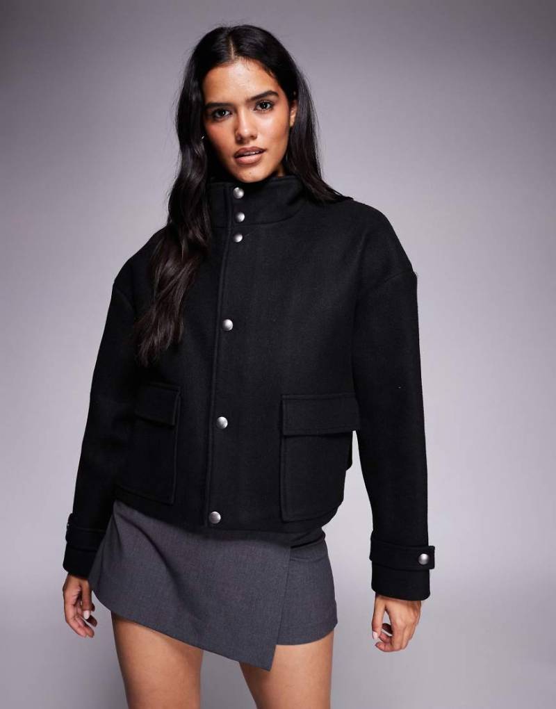 Aria Cove - Jacke in Wolloptik in Schwarz mit Trichterkragen, durchgehendem Reißverschluss und Taschendetail Aria Cove - Jacke in Wolloptik in Schwarz mit Trichterkragen, durchgehendem Reißverschluss und Taschendetail von Aria Cove