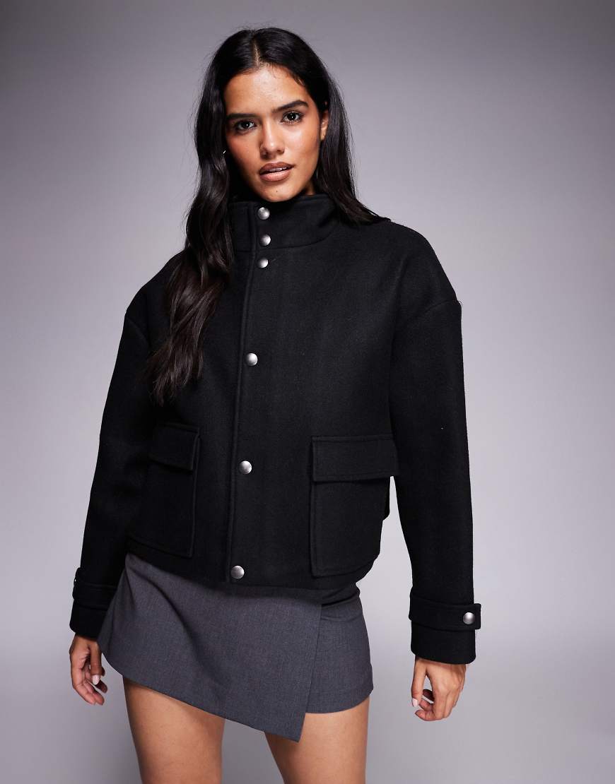 Aria Cove - Jacke in Wolloptik in Schwarz mit Trichterkragen, durchgehendem Reißverschluss und Taschendetail von Aria Cove