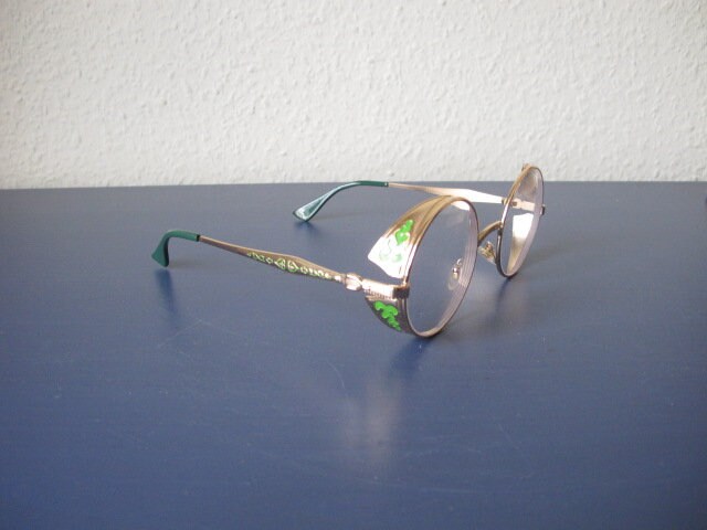 Runde Metallbrille Goldfarben Mit Applikationen in Form Von Schutzschildern von BRILLAkntrbnt