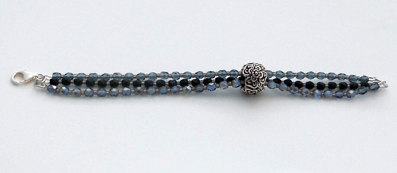 Eine Detaillierte Blumenmuster Gleitet Zinn Perle Auf Drei Stränge Aus Facettiertem Glas, Zwei Ozeanblau, Eines Schwarz; Und Kleinen Grauen Eine Detaillierte Blumenmuster Gleitet Zinn Perle Auf Drei Stränge Aus Facettiertem Glas, Zwei Ozeanblau, Eines Schwarz; Und Kleinen Grauen von BeadsByBurch