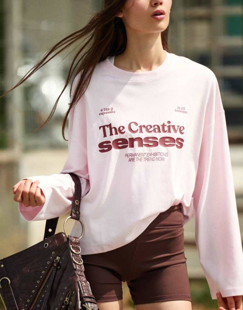 Bershka - Langärmliges, kastiges T-Shirt in Rosa mit Print Bershka - Langärmliges, kastiges T-Shirt in Rosa mit Print von Bershka