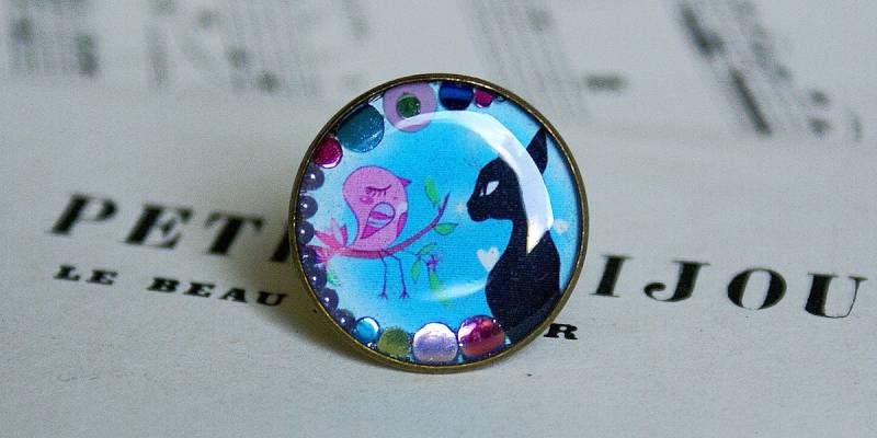 Verstellbarer Ring Mit Einem Bild Von Schwarzer Katze Und Rosa Vogel Verstellbarer Ring Mit Einem Bild Von Schwarzer Katze Und Rosa Vogel von COMME1ange