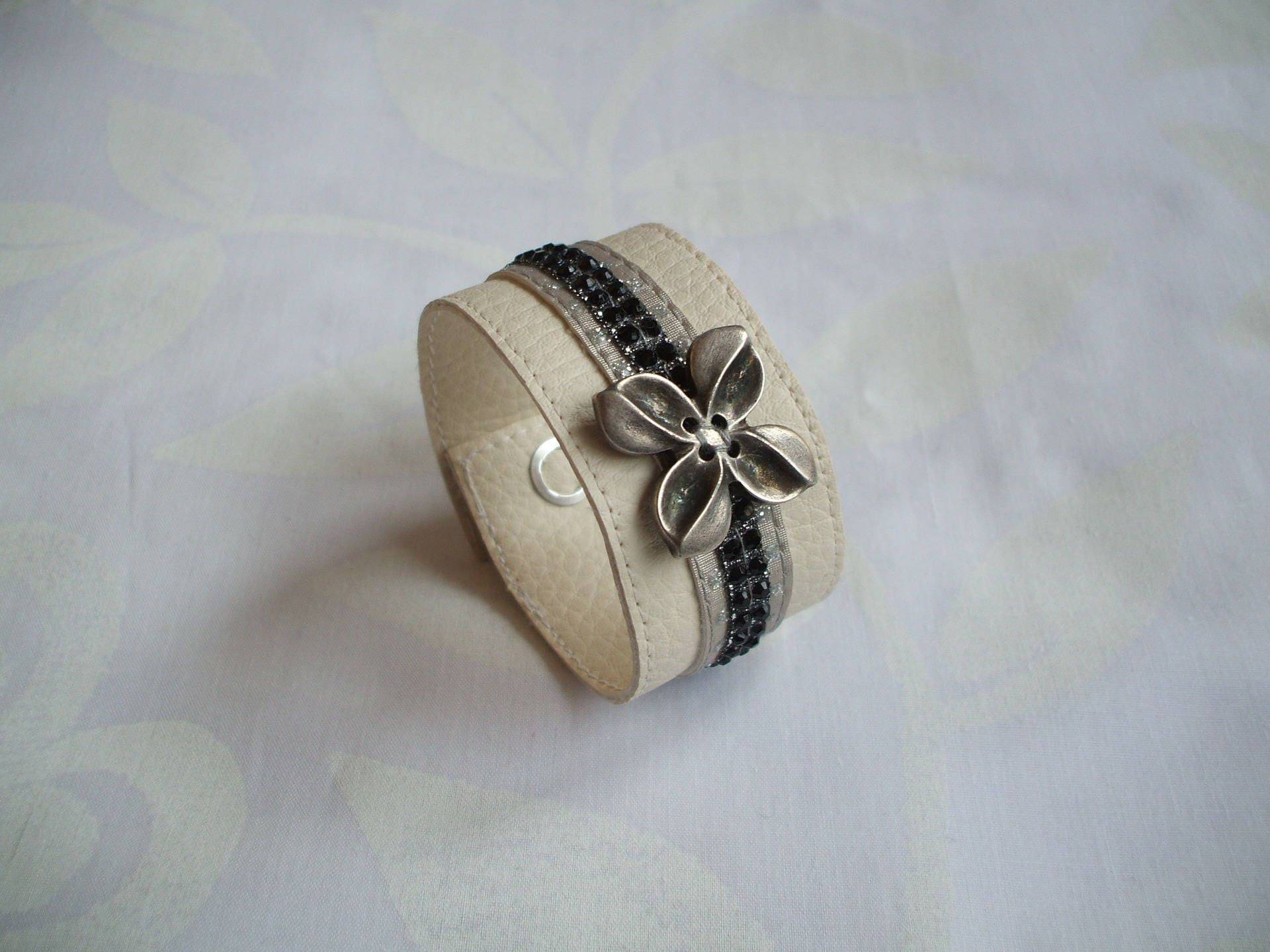 Manschettenarmband Aus Ecrufarbenem Kunstleder, Strassbändern Und Stilisierter Blume Manschettenarmband Aus Ecrufarbenem Kunstleder, Strassbändern Und Stilisierter Blume von CREATIONSMURIELHULOT