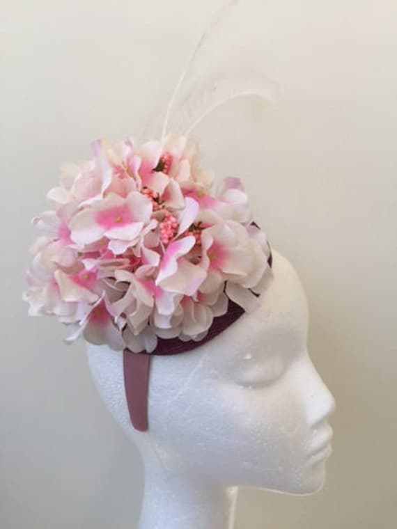 Hübscher Rosafarbener Hortensien Fascinator Auf Einer Lilafarbenen Sinamay Basis Mit Weißen Federn Hübscher Rosafarbener Hortensien Fascinator Auf Einer Lilafarbenen Sinamay Basis Mit Weißen Federn von CanteringDesigns