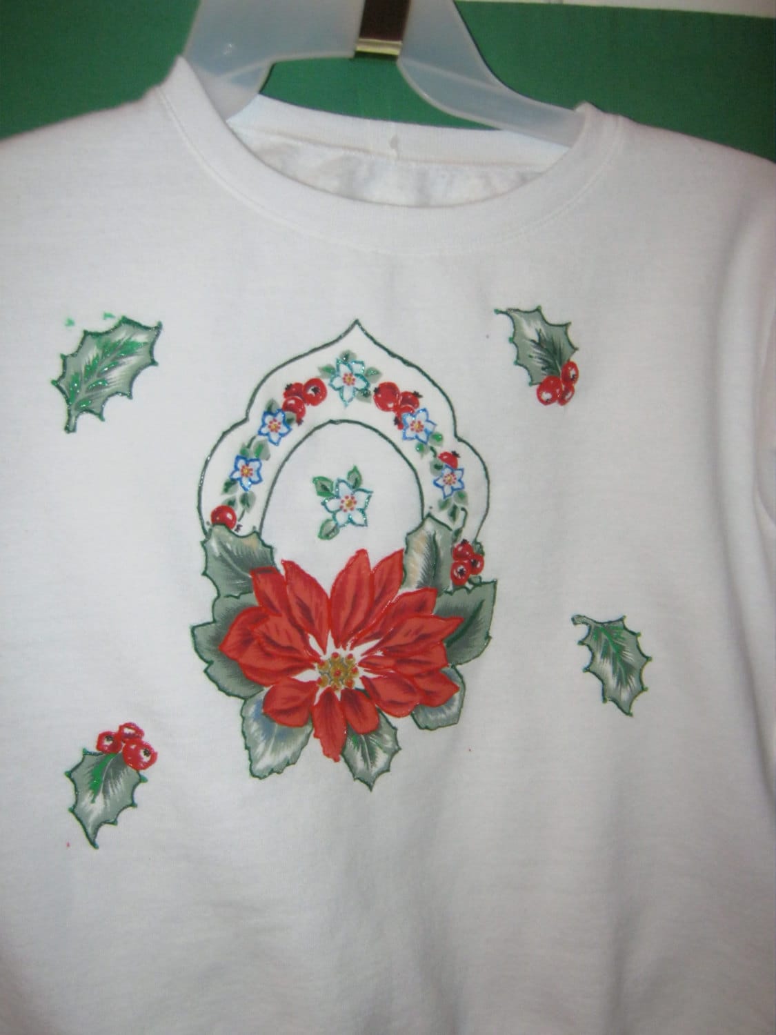 Weißes Sweatshirt Mit Poinsettia-Applikation. Apllique Zeigt Einen Weihnachtsstern, Umgeben Von Beeren Und Blättern Der Stechpalme Weißes Sweatshirt Mit Poinsettia-Applikation. Apllique Zeigt Einen Weihnachtsstern, Umgeben Von Beeren Und Blättern Der Stechpalme von CathysFashions