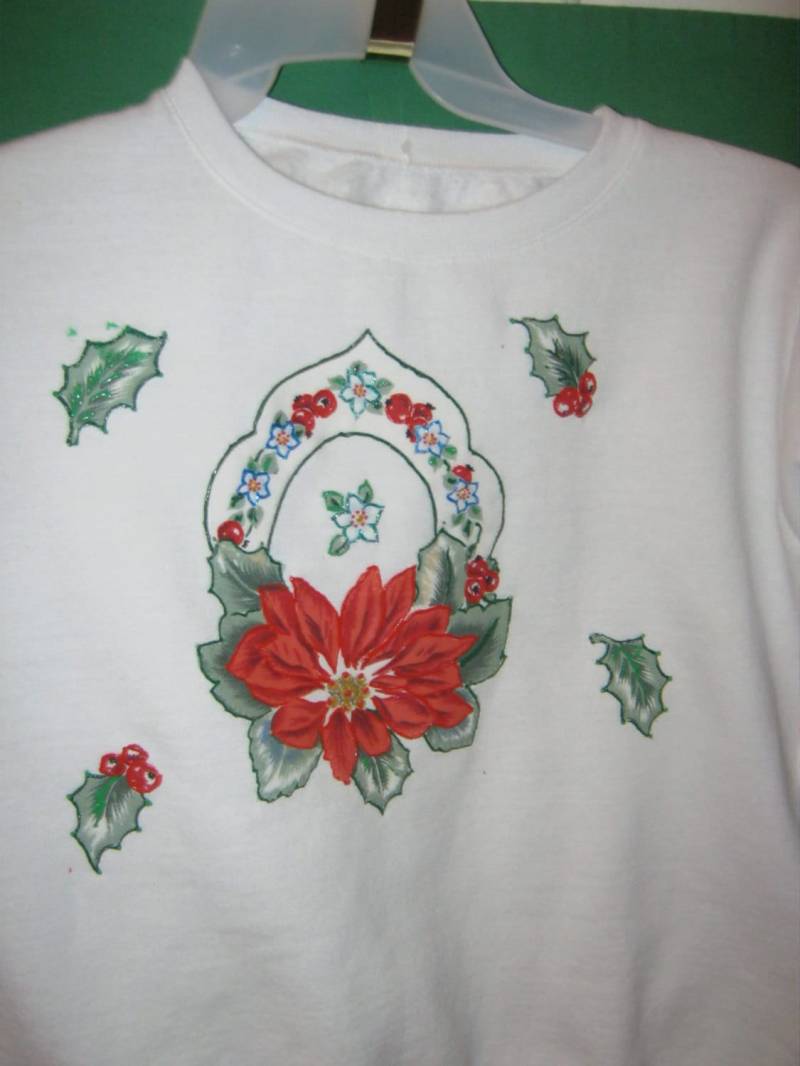 Weißes Sweatshirt Mit Poinsettia-Applikation. Apllique Zeigt Einen Weihnachtsstern, Umgeben Von Beeren Und Blättern Der Stechpalme Weißes Sweatshirt Mit Poinsettia-Applikation. Apllique Zeigt Einen Weihnachtsstern, Umgeben Von Beeren Und Blättern Der Stechpalme von CathysFashions