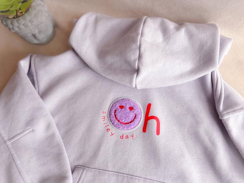 Statement-Hoodie Für Kinder "Oh Smiley Day' Mit Smiley-Patch | Hoodie Statement Und Smiley Kinder-Pullover Aufdruck Im Fliederton von DaLaLama