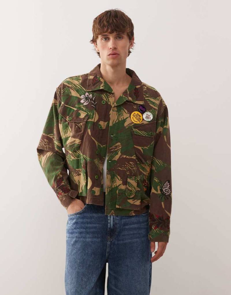 Deus Ex Machina - Ahmisa - Vintage-Jacke mit Military-Muster, platzierter Stickerei und Ansteckpins-Blau von Deus Ex Machina