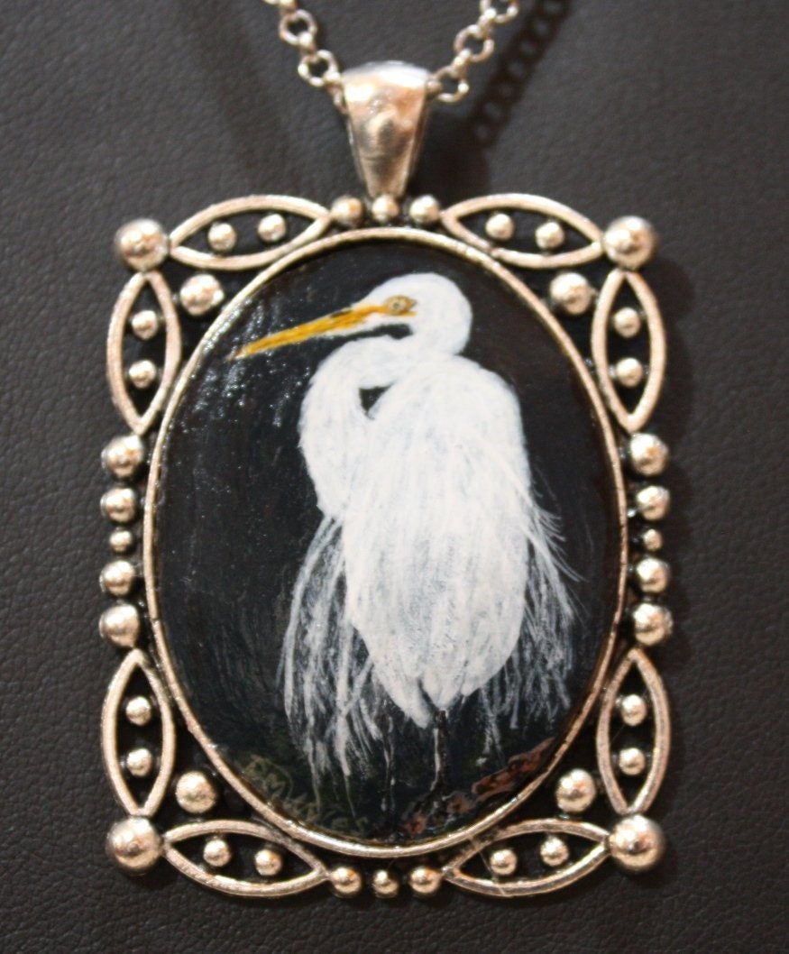 Ein Reiher in Schnee Ist Handbemalt Auf Einem Stück Kürbis, Eingefasst Einen Anhänger Mit Kette Als Einzigartige Tragbare Kunst von DianaWylesArtStudio