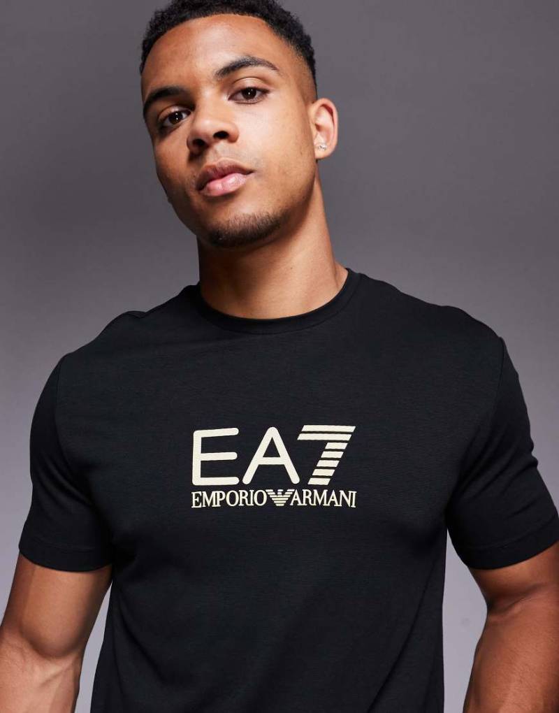 Armani - T-Shirt in Schwarz mit goldenem „EA7"-Markenlogo von EA7