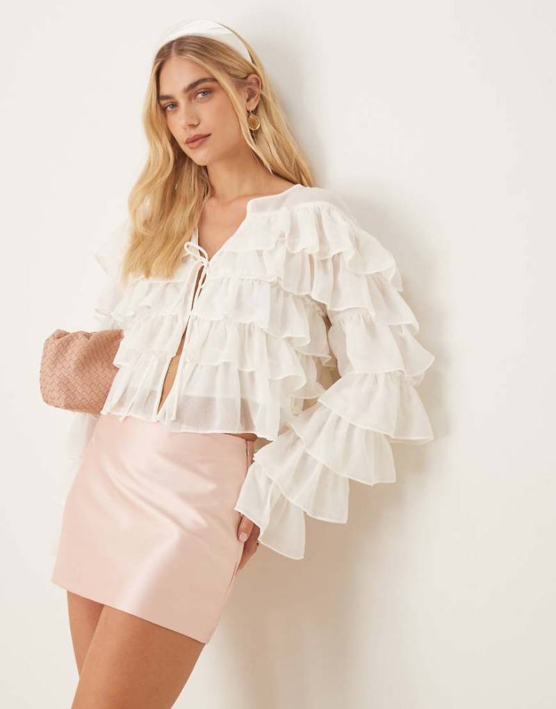 Gina Tricot - Langärmlige Cropped-Bluse in Wollweiß mit Volants-Rüschen und Bindedetail vorne Gina Tricot - Langärmlige Cropped-Bluse in Wollweiß mit Volants-Rüschen und Bindedetail vorne von GINA TRICOT