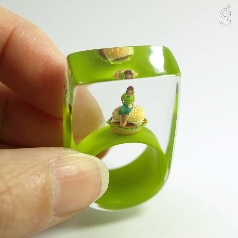 Burger-Pause - Grüner Miniaturen-Harzring Mit Einer Frau, Die Auf Einem Cheesburger Sitzt, Für Alle Fast-Food-Junkies von GeschmeideUnterTeck