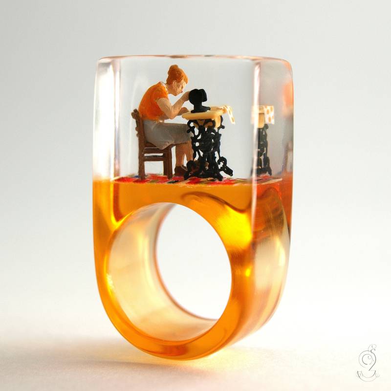 Näh-Maschine - Handgemachter Näherinnen-Ring Mit Einer Mini-Schneiderin Und Ihrer Nähmaschine Auf Orangenem Ring in Gießharz von GeschmeideUnterTeck