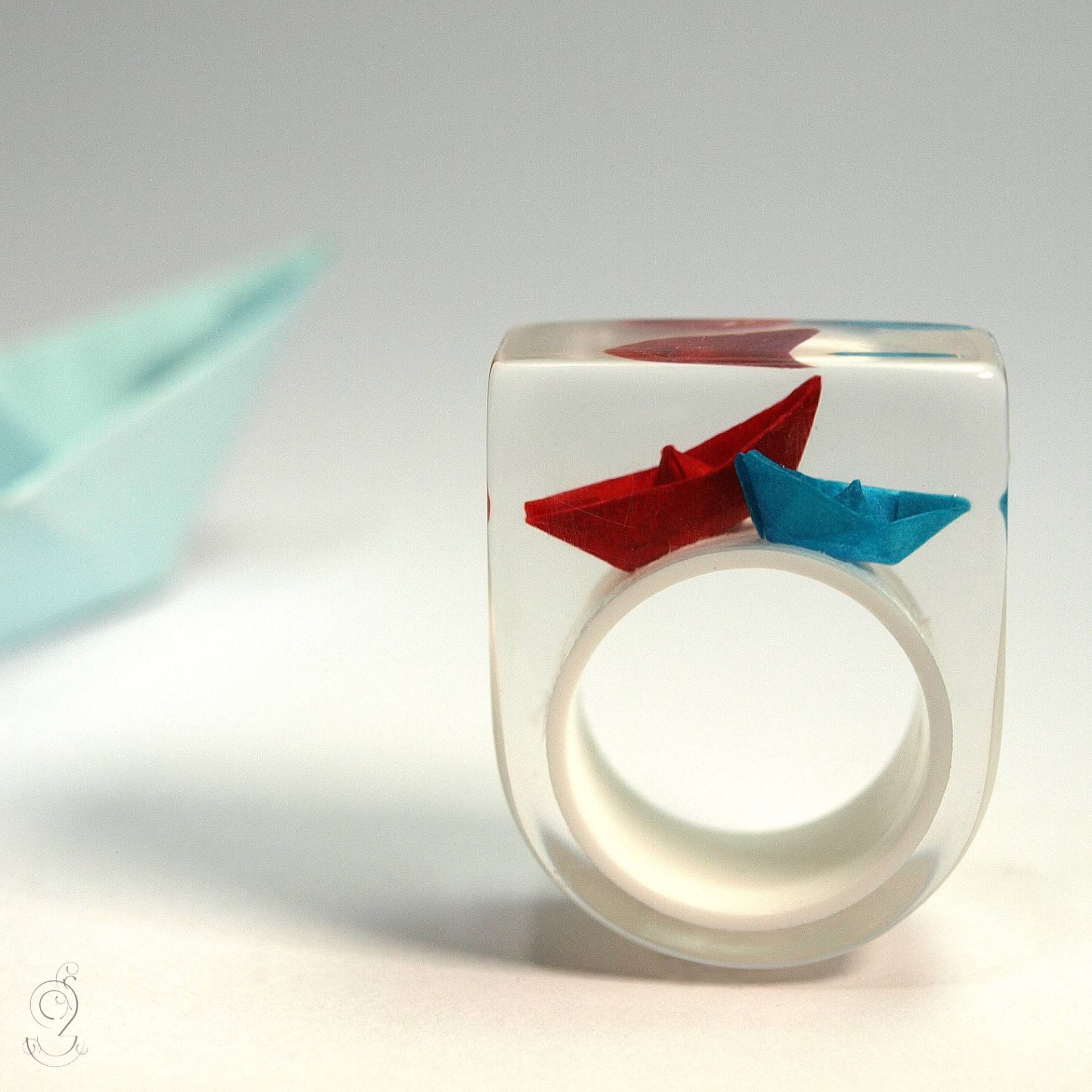 Papier-Boote-Ring "Schiff Ahoi" Mit Selbst Gefalteten Mini-Booten Aus Rotem Und Blauem Papier Auf Weißem Ring in Epoxidharz von GeschmeideUnterTeck