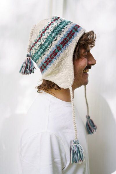 Haus of Namaste Handgefertigte Lammwollmütze mit Ohrenklappen | Fair-Isle-Strick | Haferflockenbasis mit blaugrünem und kastanienbraunem Design | Ethisch, nachhaltig und fair Haus of Namaste Handgefertigte Lammwollmütze mit Ohrenklappen | Fair-Isle-Strick | Haferflockenbasis mit blaugrünem und kastanienbraunem Design | Ethisch, nachhaltig und fair von Haus of Namaste