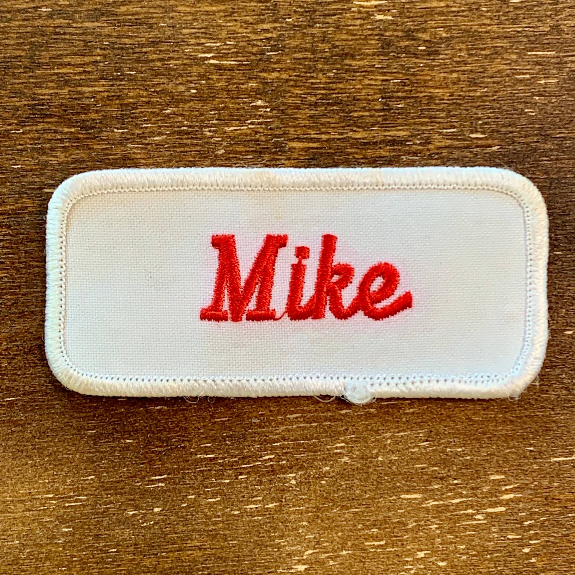 Mike. Ein Weißer Arbeitsshirt Aufnäher Mit Der Aufschrift "Mike" in Roter Schrift von HeydayRetroMart