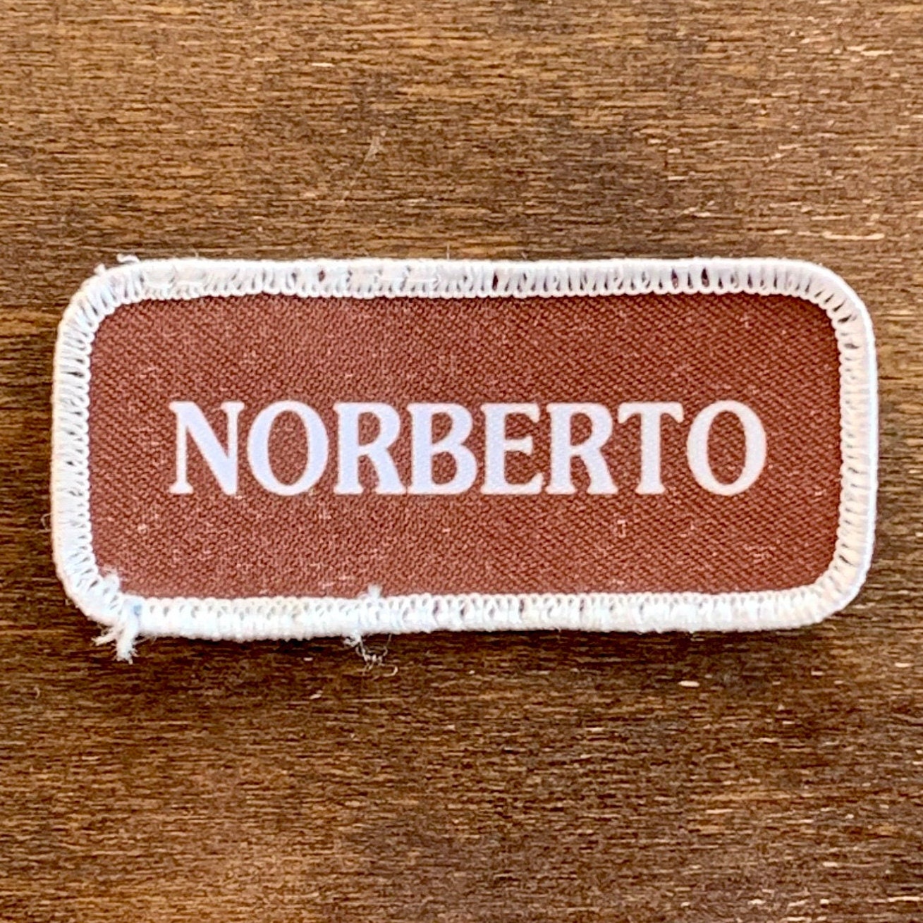 Norberto. Ein Brauner Arbeitsshirt Aufnäher Mit Der Aufschrift "Norberto" in Weißem Druck Rand von HeydayRetroMart