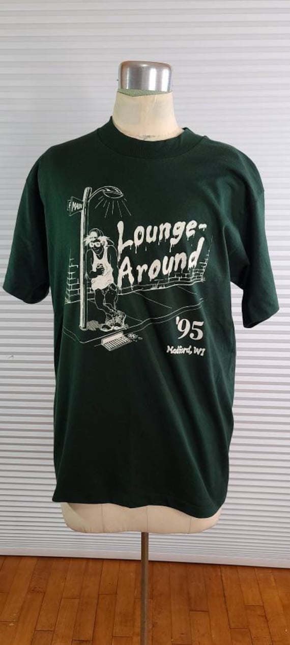 1995 "Lounge Around' Medium T-Shirt. Cartoon Zeichnung Eines Hip 90Er Jahre Kid Mit Einer Rückwärtigen Mütze, Die Sich Gegen Einen Hellen Pfahl Beugt von HippityHistory