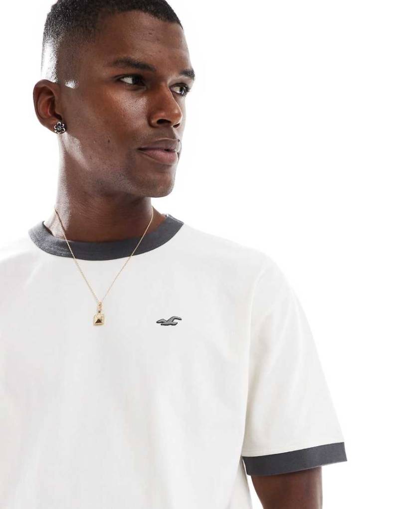 Hollister - Kastiges T-Shirt in verwaschenem Cremeweiß mit Markenlogo und kontrastierender Ziernaht am Ausschnitt-Neutral von Hollister