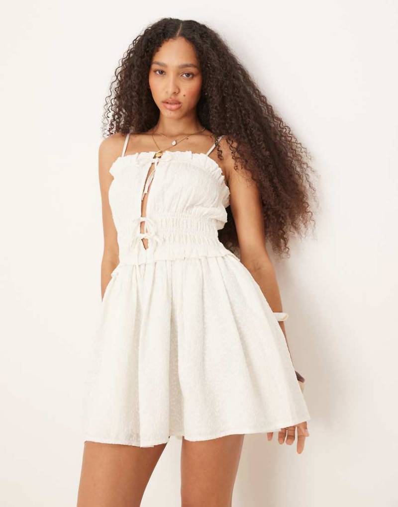 Iisla & Bird - Vorne gebundenes Minikleid in Weiß mit gesmokten Details von Iisla & Bird