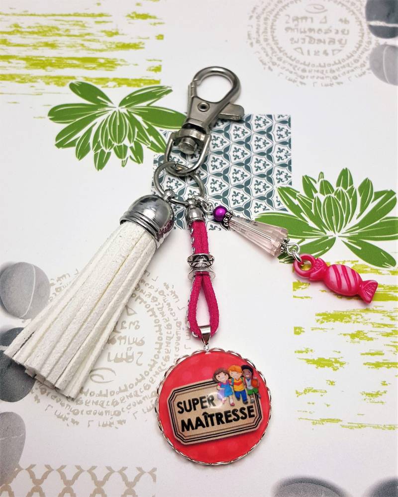 „Super Mistress"-Schlüsselanhänger Mit Glascabochon, Weißem Wildlederbommel Und Rosa Bonbonanhänger „Super Mistress"-Schlüsselanhänger Mit Glascabochon, Weißem Wildlederbommel Und Rosa Bonbonanhänger von Janyscrea