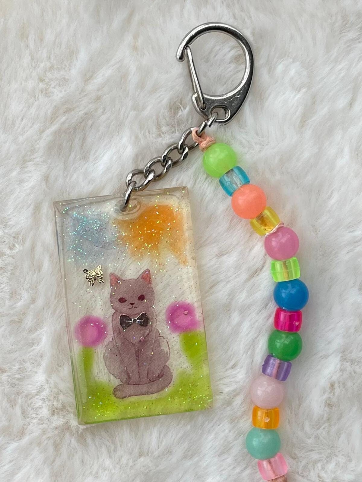 Handgemachter Taschenanhänger Für Kinder - Katze Auf Der Wiese Mit Bunten Perlen, Geschenk Zum Geburtstag von KASANUmemoryinresin