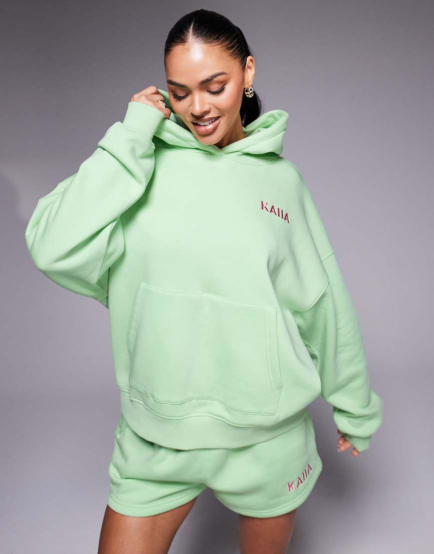 Kaiia - Oversize-Kapuzenpullover in Limettengrün mit „Miami Beach"-Palmenprint auf dem Rücken, Kombiteil Kaiia - Oversize-Kapuzenpullover in Limettengrün mit „Miami Beach"-Palmenprint auf dem Rücken, Kombiteil von Kaiia