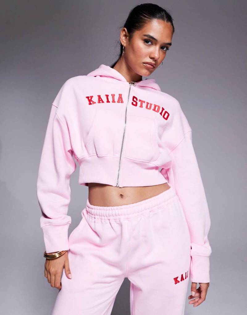 Kaiia - Cropped-Kapuzejacke aus Baumwollmix in Babyrosa mit Reißverschluss und aufgesticktem „Studio"-Logo in Rot, Kombiteil von Kaiia