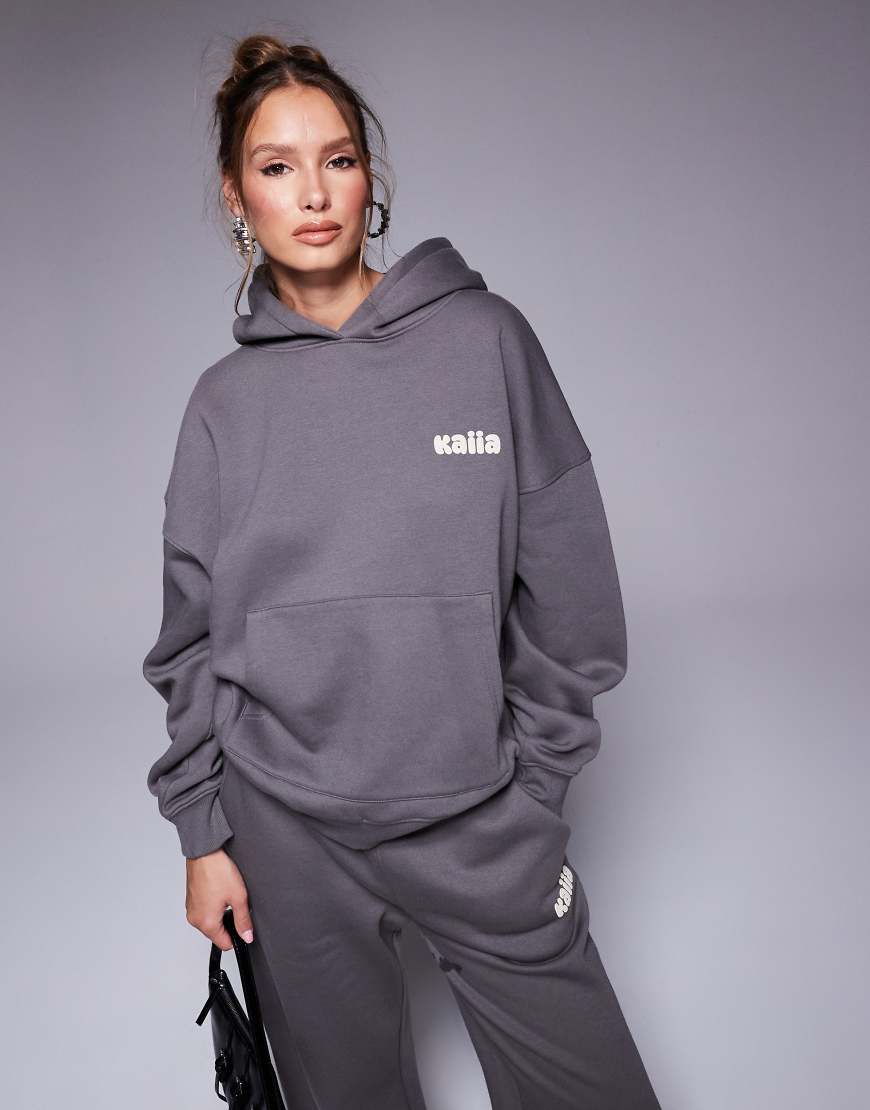 Kaiia Studio - Oversize-Kapuzenpullover in Dunkelgrau und Gelb mit Bubble-Logo auf dem Rücken, Kombiteil Kaiia Studio - Oversize-Kapuzenpullover in Dunkelgrau und Gelb mit Bubble-Logo auf dem Rücken, Kombiteil von Kaiia