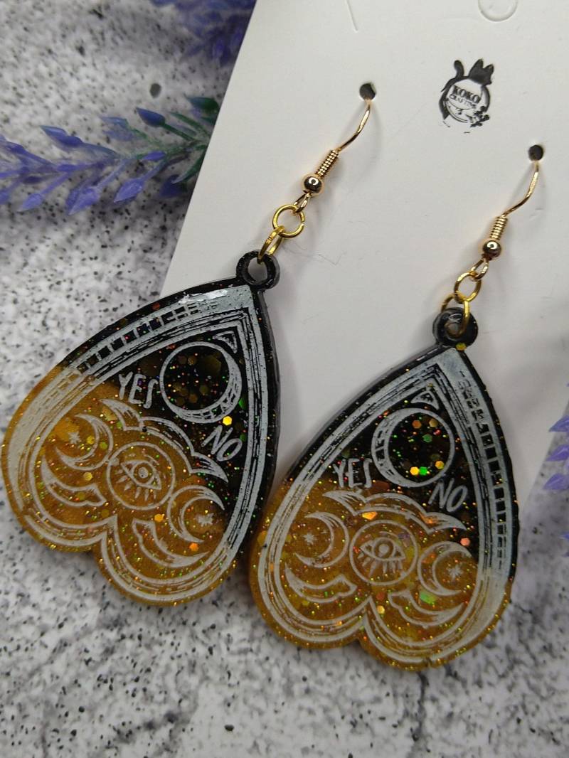 Quija Planchette Ohrringe Schwarz-Gold Mit Glitterpartikeln Die Regenbogenfarben Glitzern, Weiße Outlines von KokoCrafting