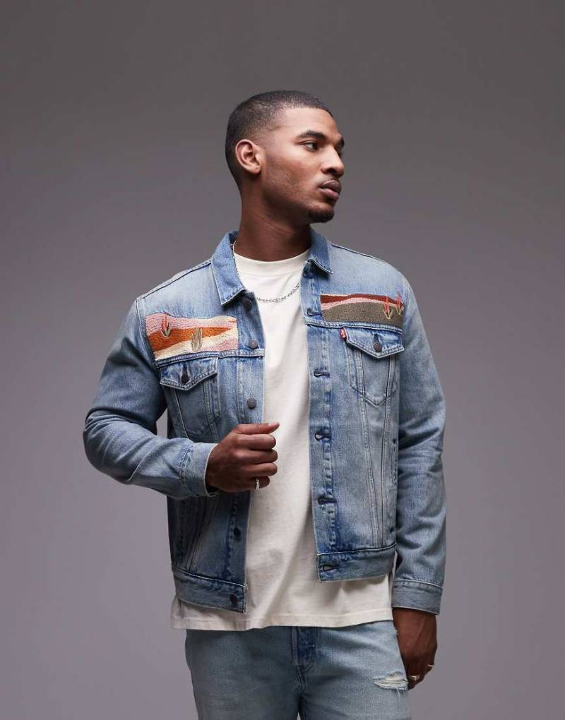 Levi's - Locker geschnittene Trucker-Jeansjacke in mittelblauer Waschung mit aufgesticktem Landschaftsmotiv, Kombiteil Levi's - Locker geschnittene Trucker-Jeansjacke in mittelblauer Waschung mit aufgesticktem Landschaftsmotiv, Kombiteil von Levi's