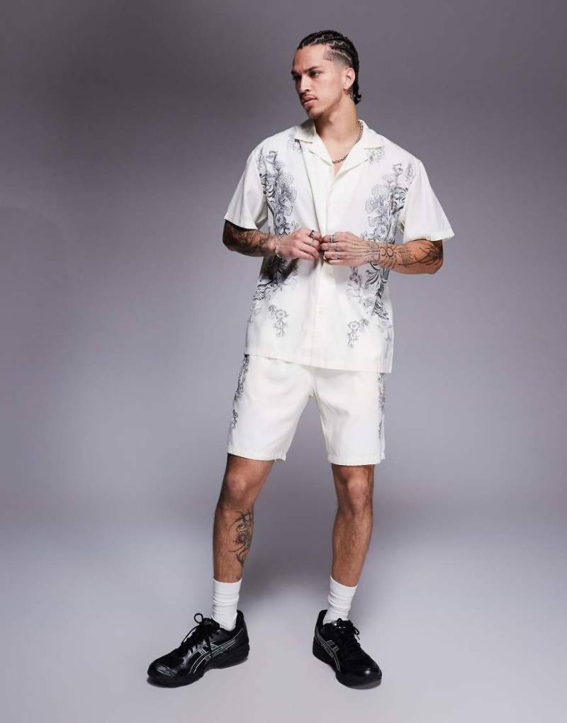 Liquor N Poker - Shorts in Wollweiß mit königlichem Emblem-Print, Kombiteil Liquor N Poker - Shorts in Wollweiß mit königlichem Emblem-Print, Kombiteil von Liquor N Poker