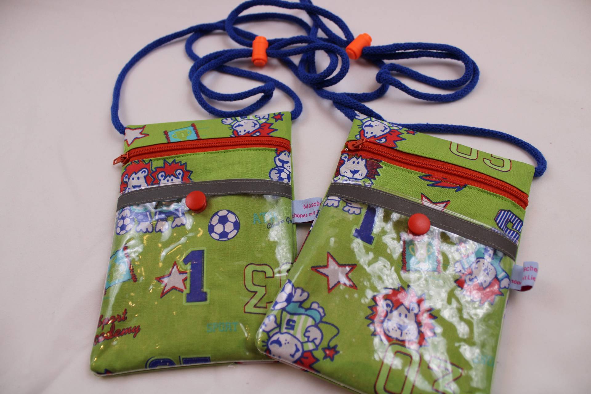 Brustbeutel/Umhängetäschchen Für Kinder "Sportsfreunde" Mit Klarsichtfach, Reflektorstreifen + Fluoresz. Kordelstopper; Fahrkartentasche Brustbeutel/Umhängetäschchen Für Kinder "Sportsfreunde" Mit Klarsichtfach, Reflektorstreifen + Fluoresz. Kordelstopper; Fahrkartentasche von Maschenwichtel