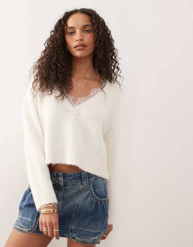 Monki - Flauschiger Strickpullover in Wollweiß mit V-Ausschnitt und Spitzenbesatz Monki - Flauschiger Strickpullover in Wollweiß mit V-Ausschnitt und Spitzenbesatz von Monki