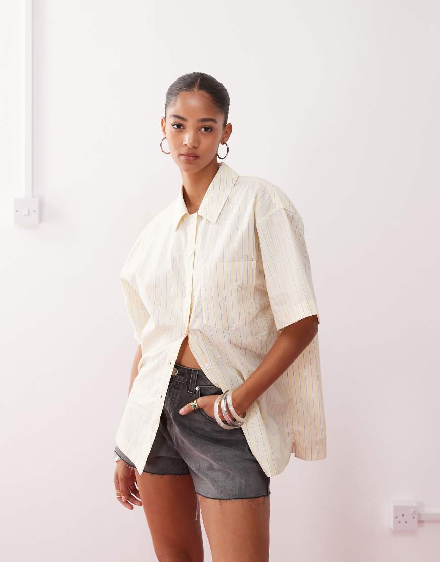 Monki - Kurzärmliges Oversize-Hemd mit weißen und buttergelben Streifen Monki - Kurzärmliges Oversize-Hemd mit weißen und buttergelben Streifen von Monki
