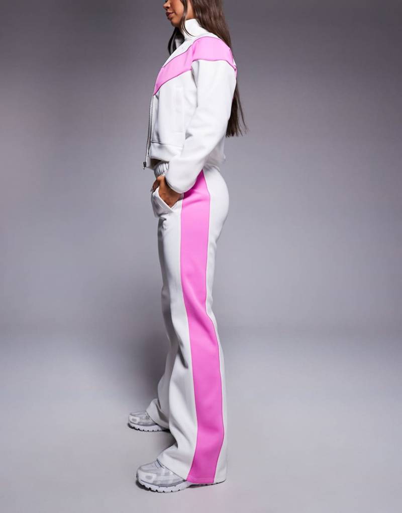 Nike - Windrunner - Polyknit-Trainingshose in Weiß und Rosa mit mittelhohem Bund Nike - Windrunner - Polyknit-Trainingshose in Weiß und Rosa mit mittelhohem Bund von Nike